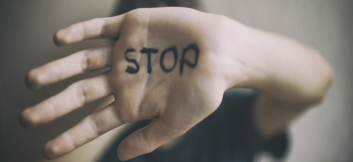 A 18-year-old guy protects himself with his hand with the inscription Stop